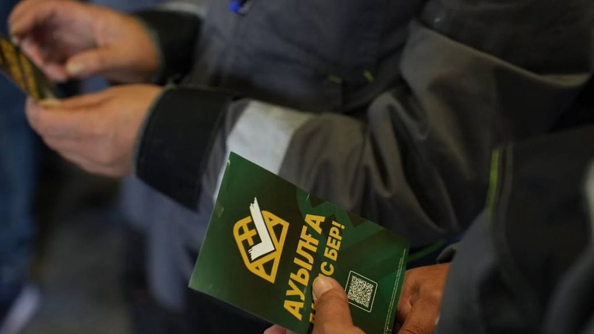 Рабочие держат буклет партии "Ауыл"