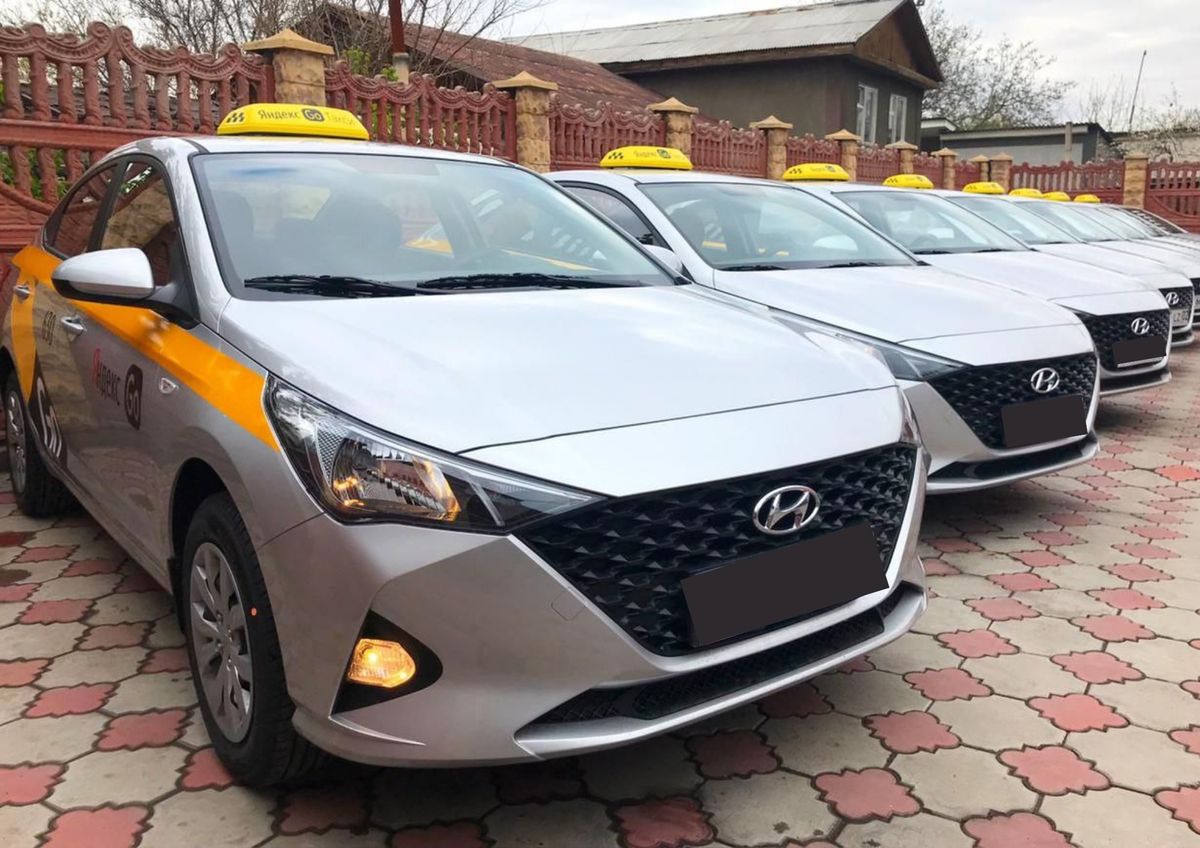 Несколько припаркованных машин, серого цвета марки Hyundai с логотипами "Яндекс.Такси"
