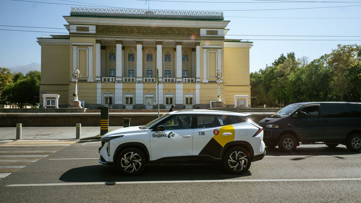 Белый кроссовер сервиса "Яндекс.Такси" на фоне театра оперы и балета им. Абая