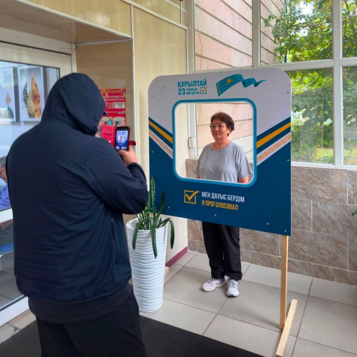 Женщина позирует для фотографии у специальной фоторамки после голосования на выборах депутатов курултая