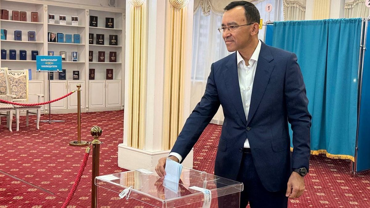 Маулен Ашимбаев опускает бюллетень в прозрачную урну на избирательном участке в Астане
