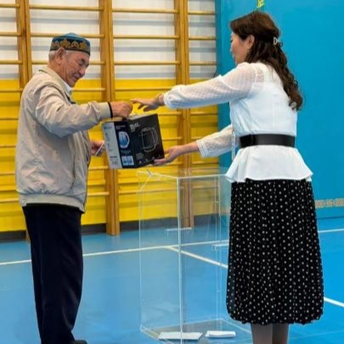 Избирателю вручают памятный подарок на одном из избирательных участков Астаны в день выборов депутатов курултая