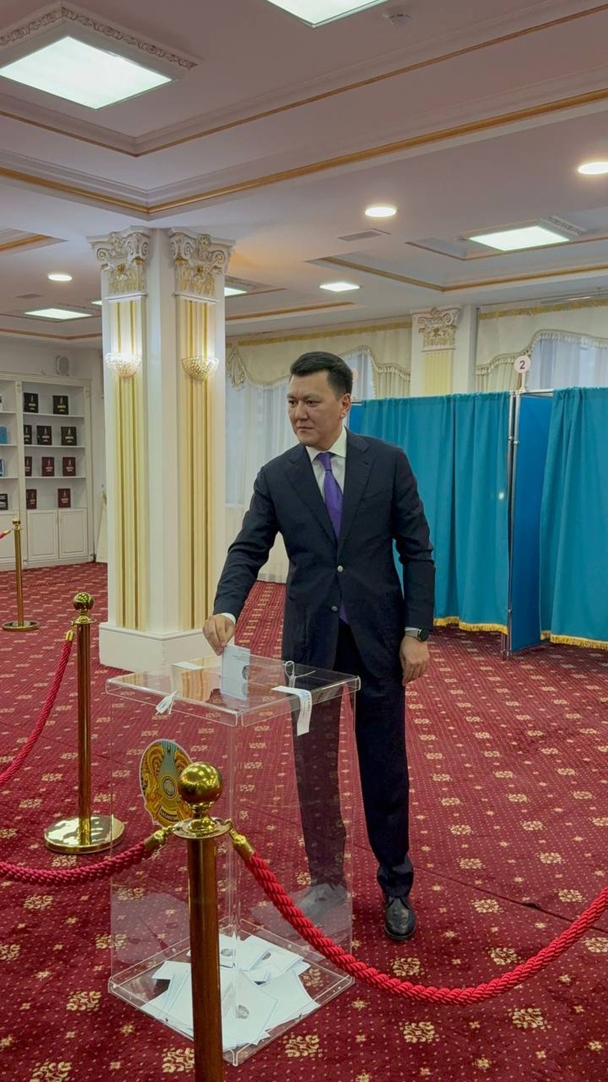 Ерлан Карин опускает бюллетень в прозрачную урну на избирательном участке № 129 в Астане