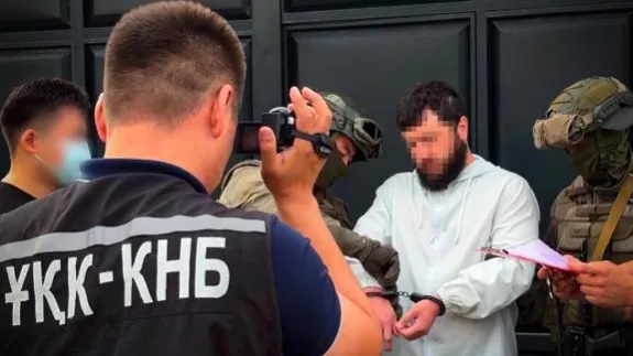 Сотрудники КНБ в экипировке проводят задержание мужчины в наручниках
