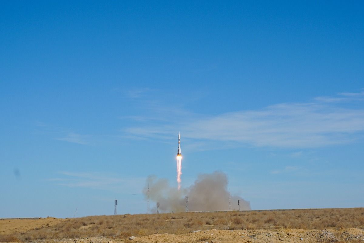 Ракета взлетает с космодрома Байконур над казахстанской степью на фоне ясного голубого неба