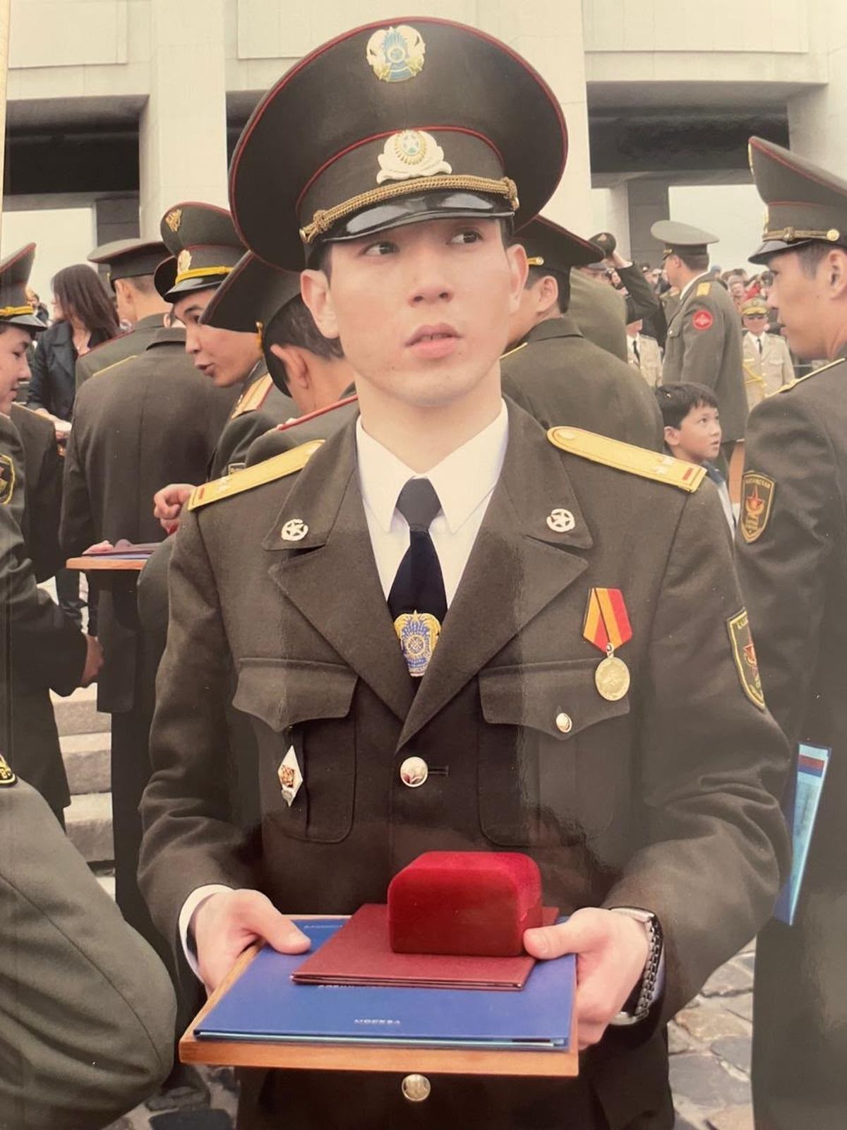 Алибек Тналиев в форме держит в руках документы