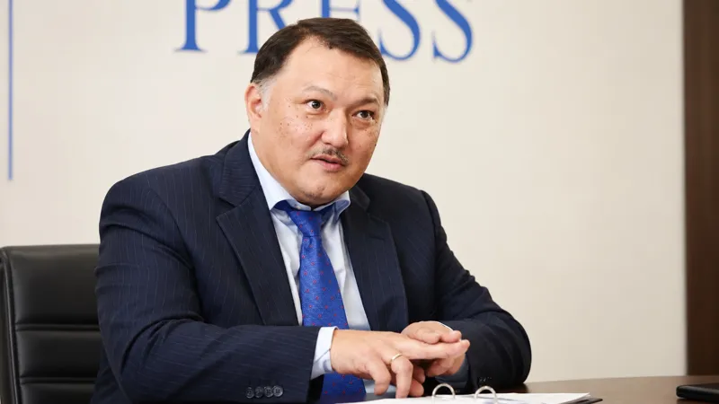 Нурлан Жумасултанов сидит за столом во время интервью