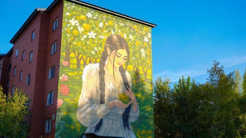 Мурал с девушкой и яблоками украсил фасад дома в Алматинском районе столицы