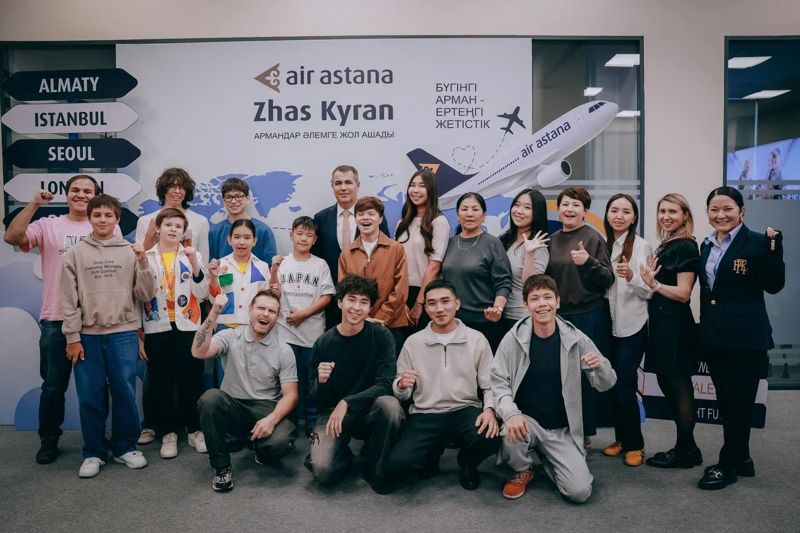 Участники программы "Жас Кыран", дети и представители Air Astana позируют для общего фото на фоне баннера проекта