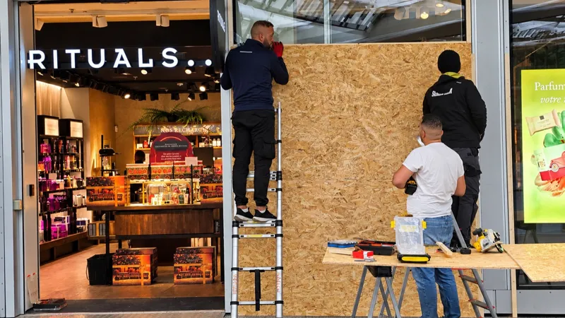 Трое рабочих устанавливают деревянные панели перед витриной магазина Rituals