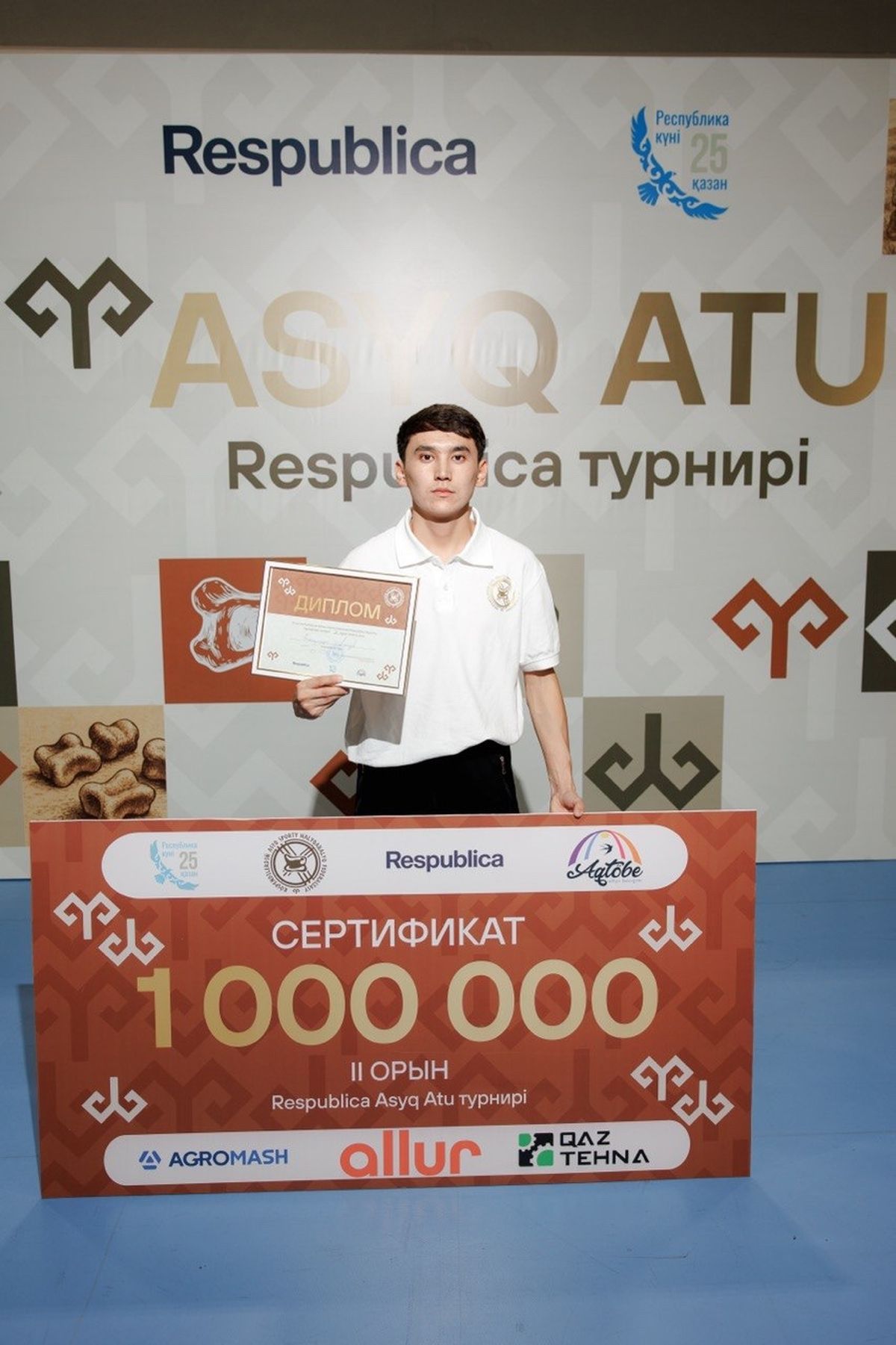Алинұр Берікқазыұлы Ақтөбеде өткен асық ату турнирінде 1 миллион теңгенің сертификаты мен дипломын ұстап тұр